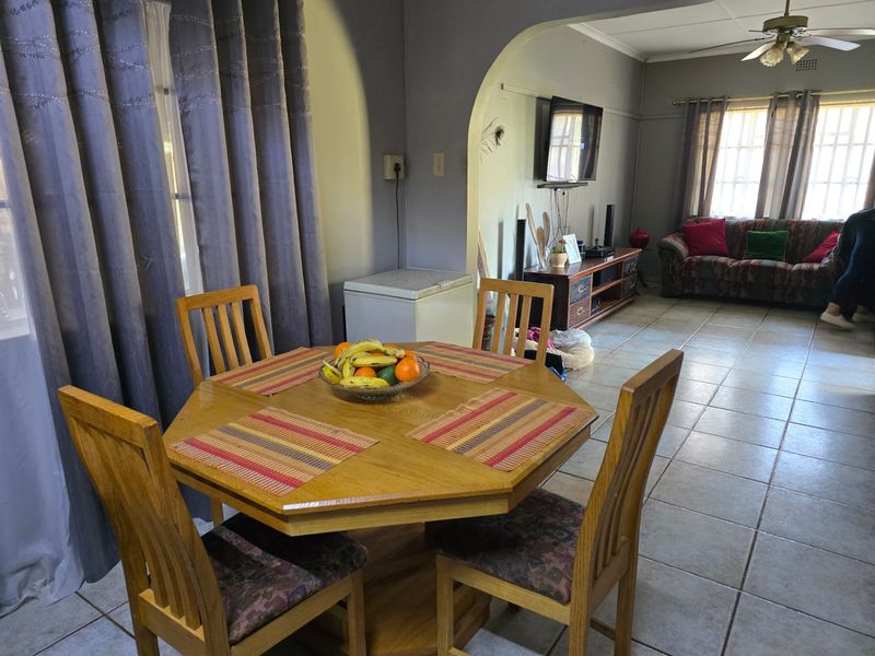 Open plan living and dining area featuring tiled flooring, a ceiling fan, and an arched transition between the two spaces.