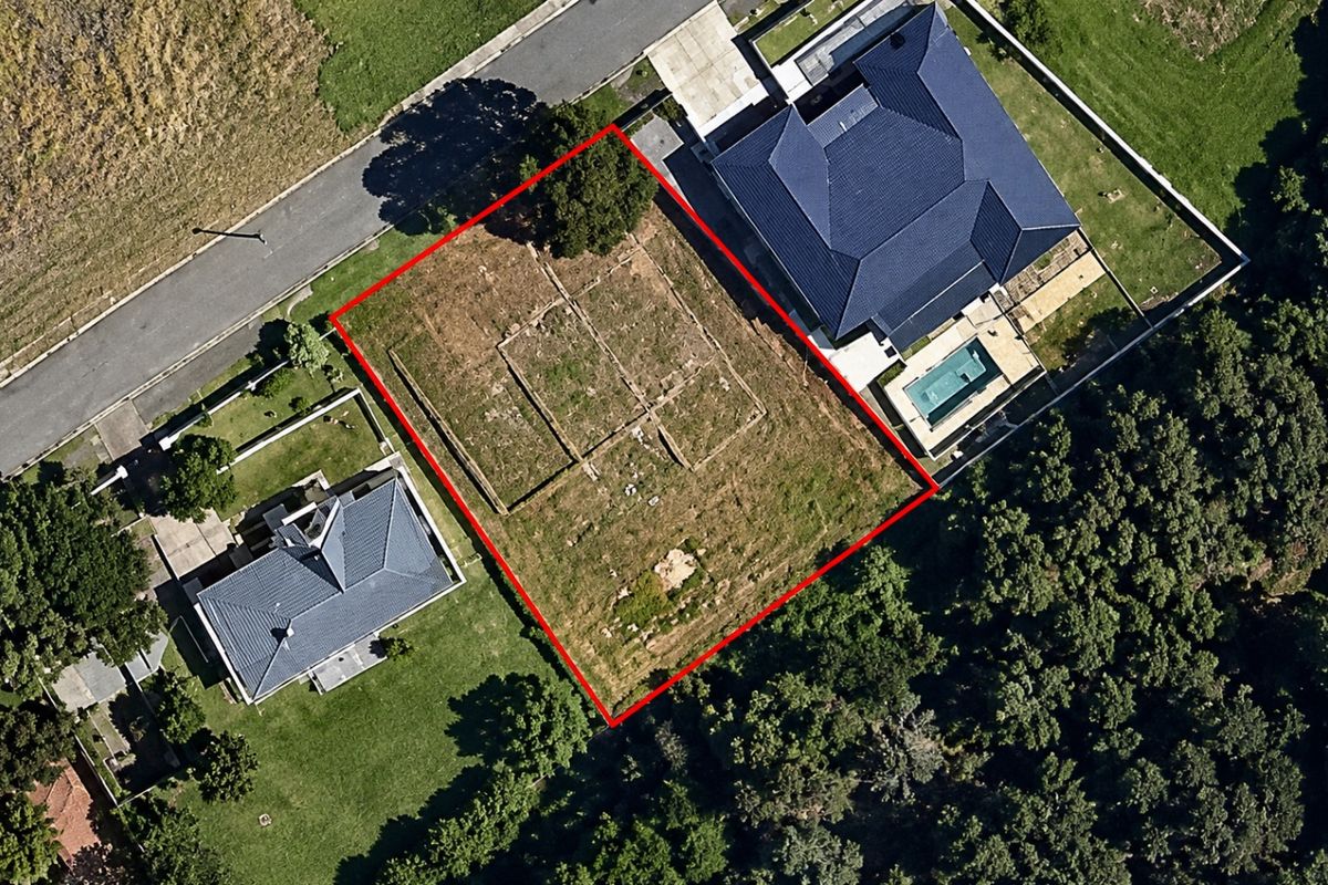 Aerial view of a vacant residential land plot outlined in red, situated between existing developed properties in a suburban neighborhood.