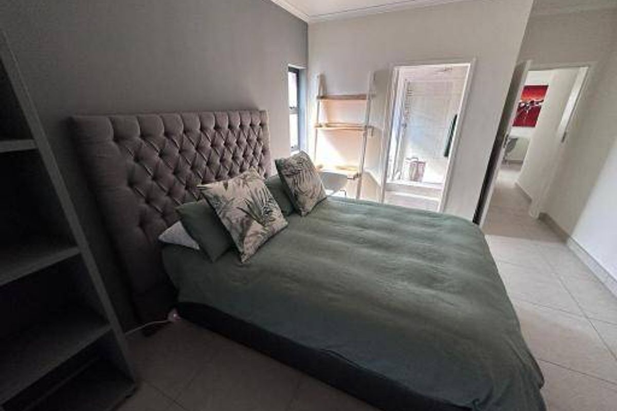 A well-maintained bedroom featuring tiled flooring, built-in shelving, and direct access to an en-suite bathroom.