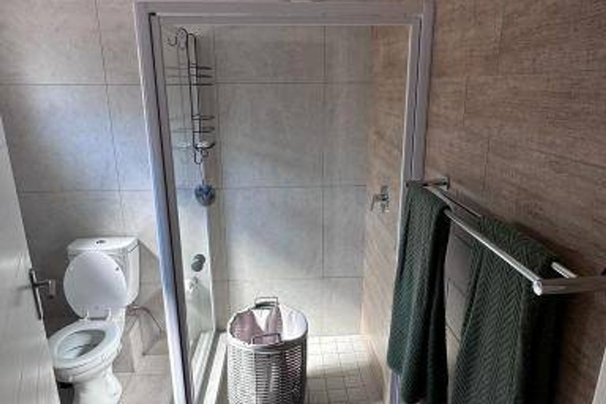 A modern bathroom featuring a glass-enclosed shower, tiled walls with wood-look accents, and a standard toilet.