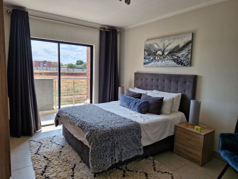 A well-maintained bedroom featuring tiled flooring and a large sliding glass door providing direct access to a private balcony.