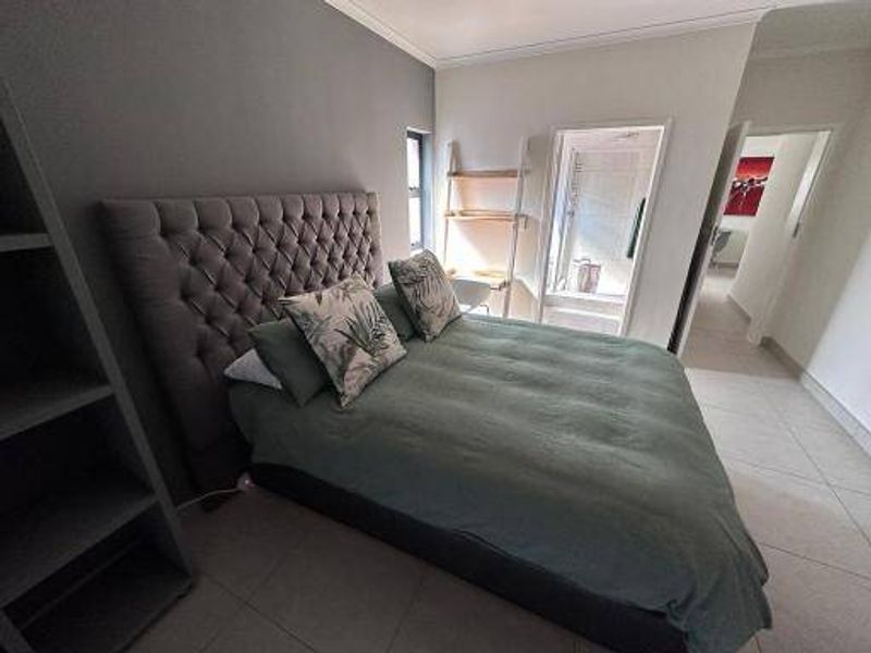 A well-maintained bedroom featuring tiled flooring, built-in shelving, and direct access to an en-suite bathroom.