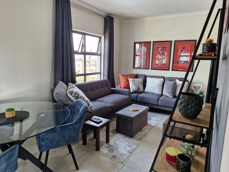 A well-maintained living room featuring tiled flooring and a large aluminium-framed window, providing a comfortable and functional space.