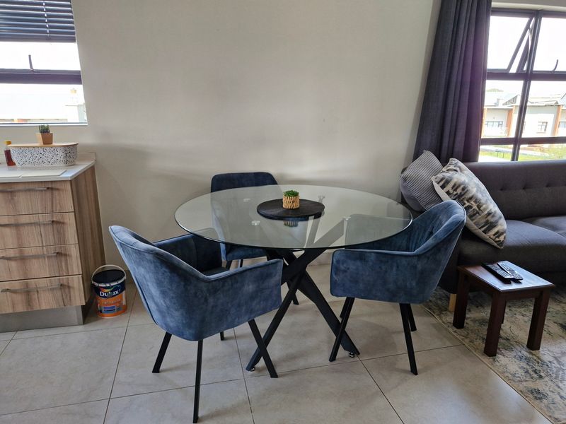 Open plan living and dining area featuring tiled flooring and modern aluminium window frames, creating a bright and functional space.