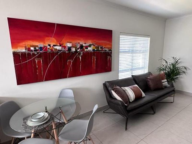 A bright living area featuring neutral tiled flooring and venetian blinds, creating a clean and modern space.