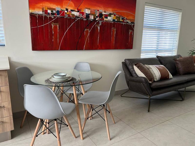 A bright open-plan living and dining area featuring neutral tiled flooring and modern venetian blinds, creating a clean and functional space.