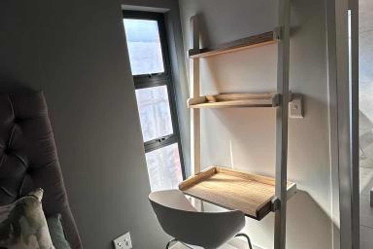 A well-lit bedroom corner featuring tiled flooring, a modern aluminium window, and neutral wall finishes.