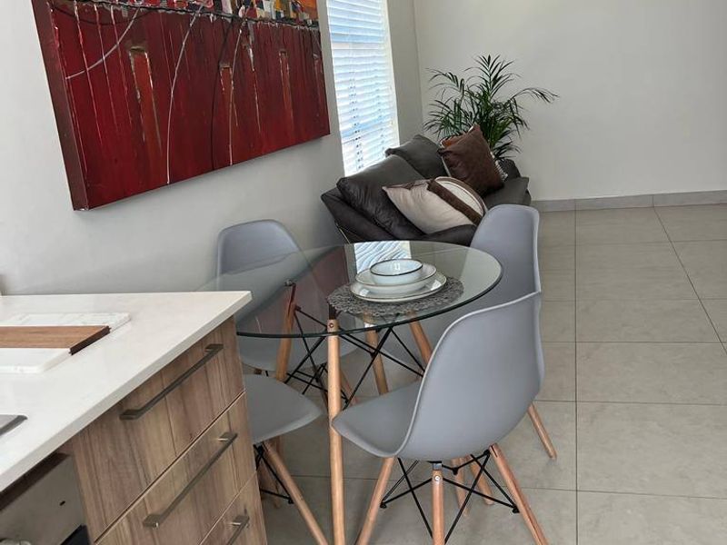 Open plan living and dining area featuring modern kitchen cabinetry, built-in oven, tiled flooring, and large windows with venetian blinds.