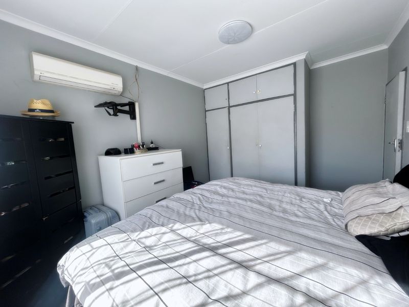A functional bedroom featuring built-in cupboards, a split-system air conditioner, and neutral wall finishes.