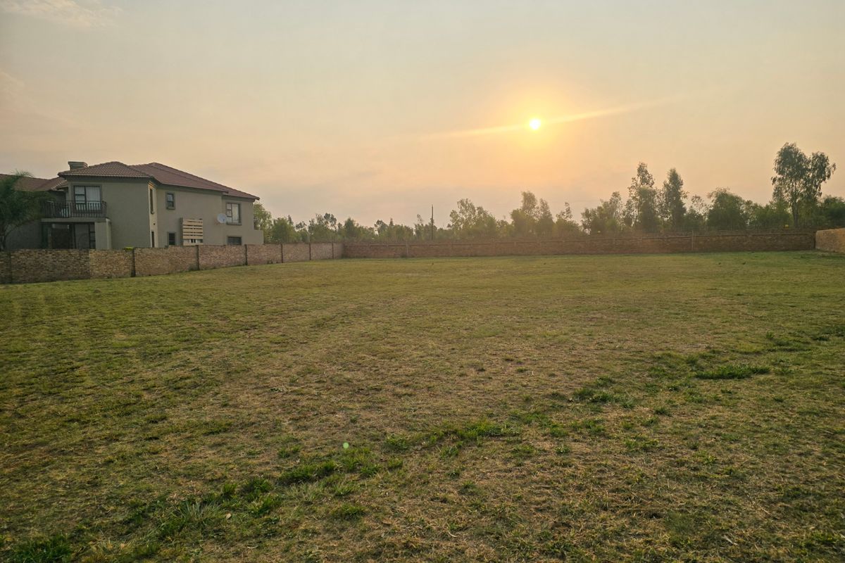 A spacious, level residential plot featuring a well-maintained grass lawn and enclosed by a perimeter brick wall.