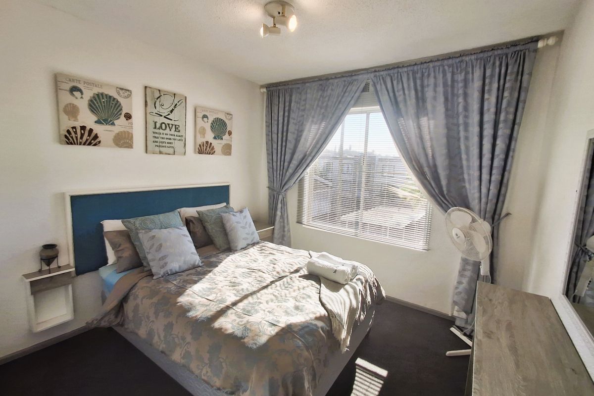 A well-lit bedroom featuring a window with venetian blinds and curtain tracks, providing a comfortable and functional living space.