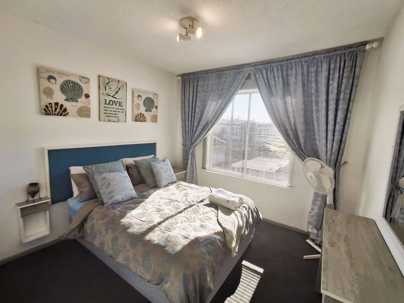 A well-lit bedroom featuring a window with venetian blinds and curtain tracks, providing a comfortable and functional living space.