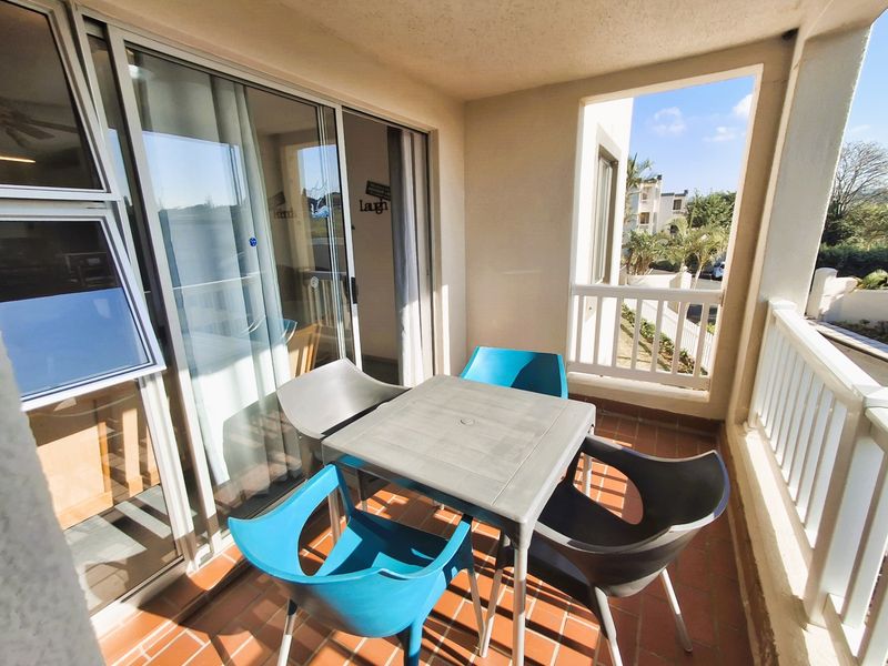 A covered balcony featuring tiled flooring and sliding glass door access to the interior living space.