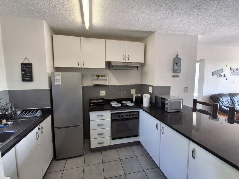 A functional kitchen featuring granite countertops, built-in cabinetry, a stainless steel oven with hob, and tiled flooring.
