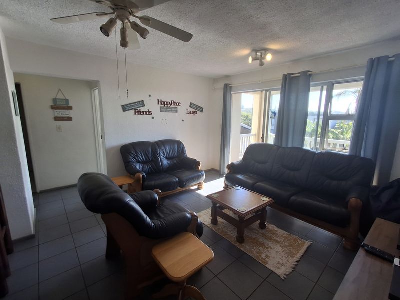 A living room featuring tiled flooring, a ceiling fan, and a sliding glass door providing access to an outdoor balcony area.