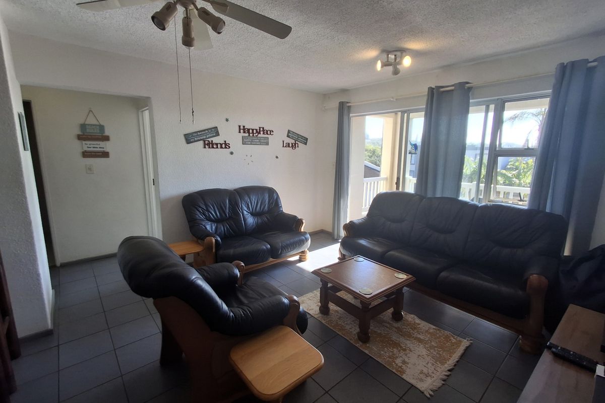 A living room featuring tiled flooring, a ceiling fan, and a sliding glass door providing access to an outdoor balcony area.