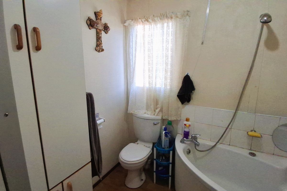 A compact bathroom featuring a bathtub with a handheld shower mixer, a toilet, and built-in storage cabinetry.
