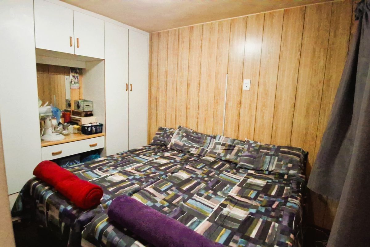 A bedroom featuring built-in cupboards and wood-look wall paneling, offering a functional space with potential for cosmetic updates.