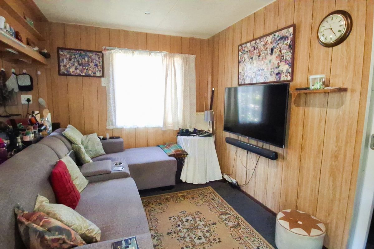 A living room featuring wood-paneled walls and a window, offering a dated aesthetic that could be modernized with updated finishes.