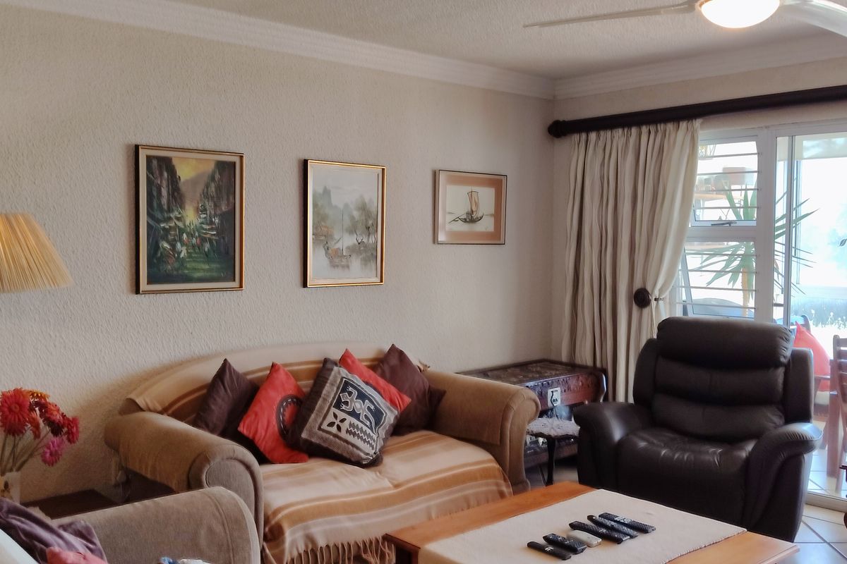 A comfortable living room featuring a ceiling fan, textured walls, and a large sliding glass door providing access to an outdoor balcony area.
