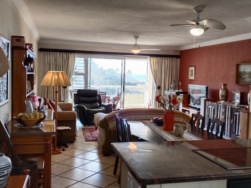 Spacious open-plan living and dining area featuring ceramic tile flooring, ceiling fans, and direct access to a balcony through sliding glass doors.