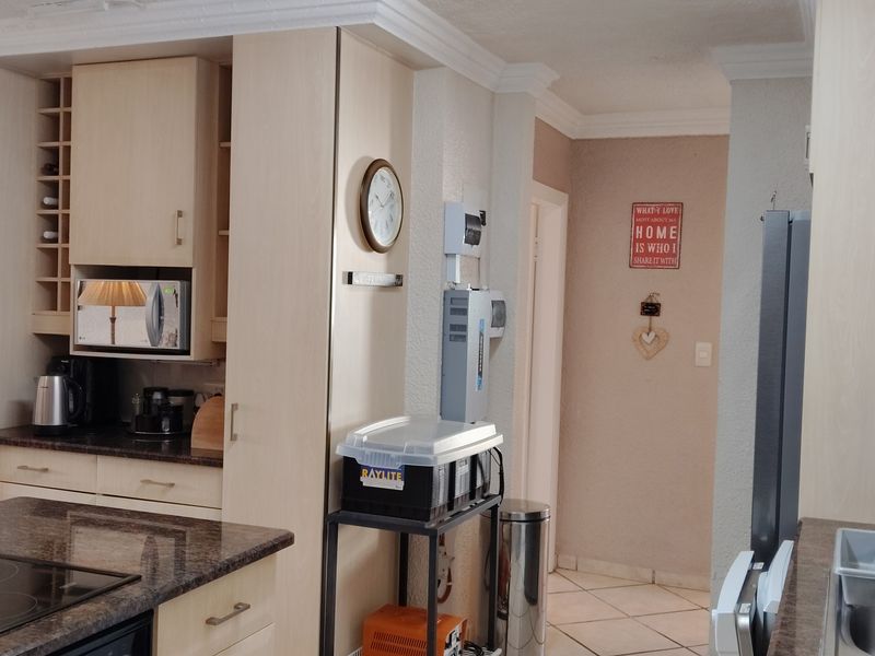 A functional kitchen featuring light-toned built-in cabinetry, granite countertops, an integrated hob, and tiled flooring, offering a practical layout for daily use.