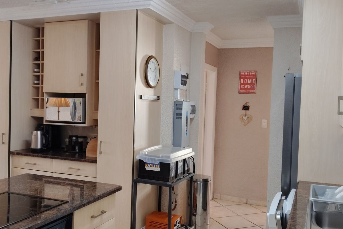 A functional kitchen featuring light-toned built-in cabinetry, granite countertops, an integrated hob, and tiled flooring, offering a practical layout for daily use.