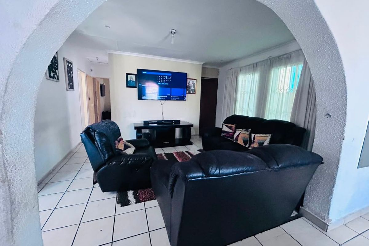 A living room featuring ceramic floor tiles and a distinctive arched entryway, providing a clear view into the main lounge area.