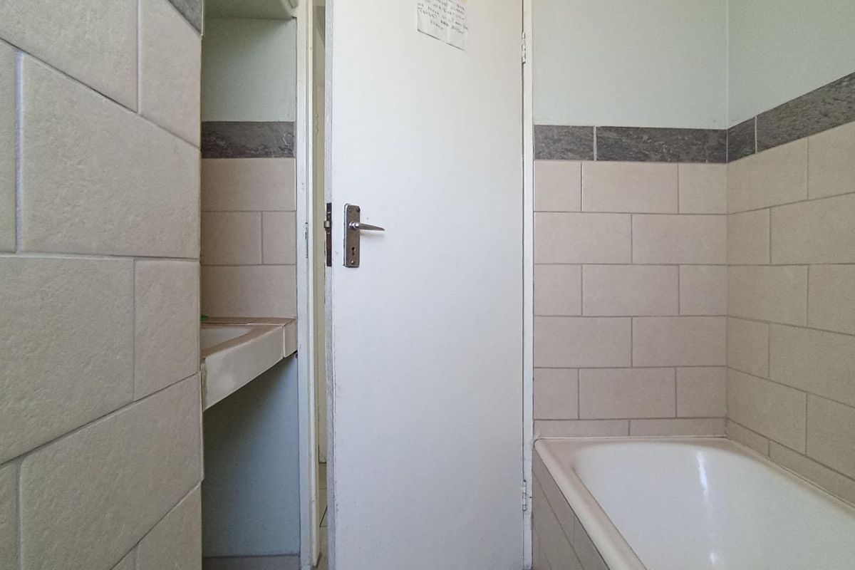A functional bathroom featuring a built-in bathtub and a separate vanity area with tiled wall finishes.