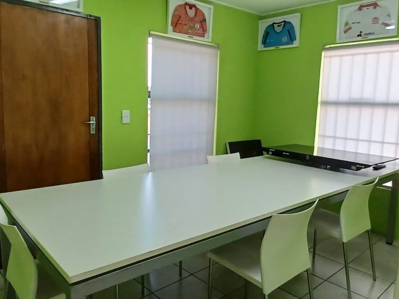 A functional office space featuring tiled flooring and roller blinds, suitable for a professional work environment.