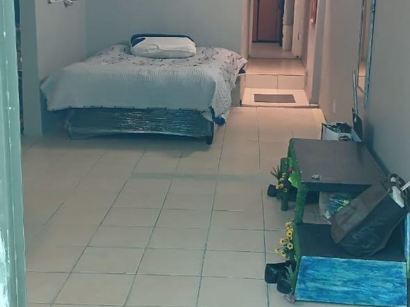 A bedroom featuring tiled flooring and a sloped ceiling, providing a functional living space with direct access to an adjoining area.