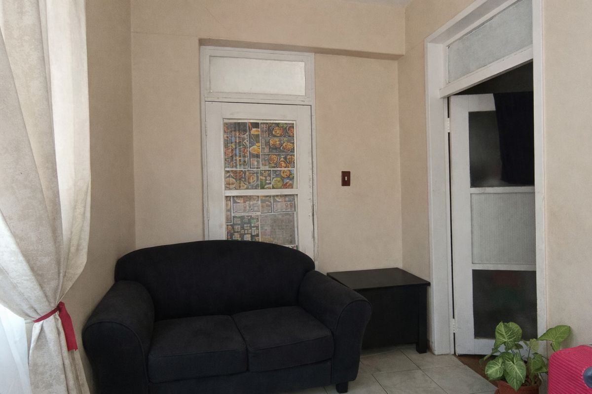 A living area featuring tiled flooring and a multi-panel interior door with a transom window, requiring cosmetic updates to improve the overall aesthetic.