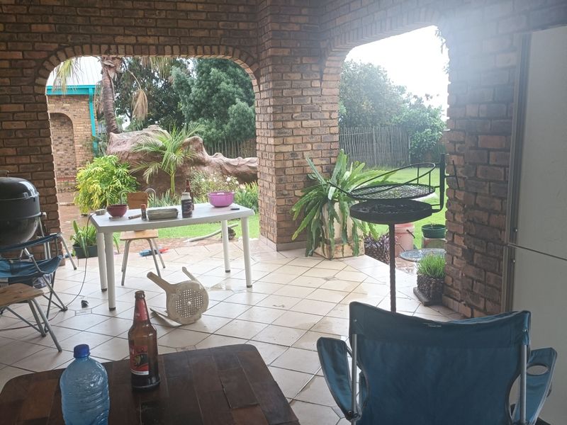 A covered outdoor patio area featuring exposed brick pillars and tiled flooring, providing a functional space for outdoor relaxation and entertainment.