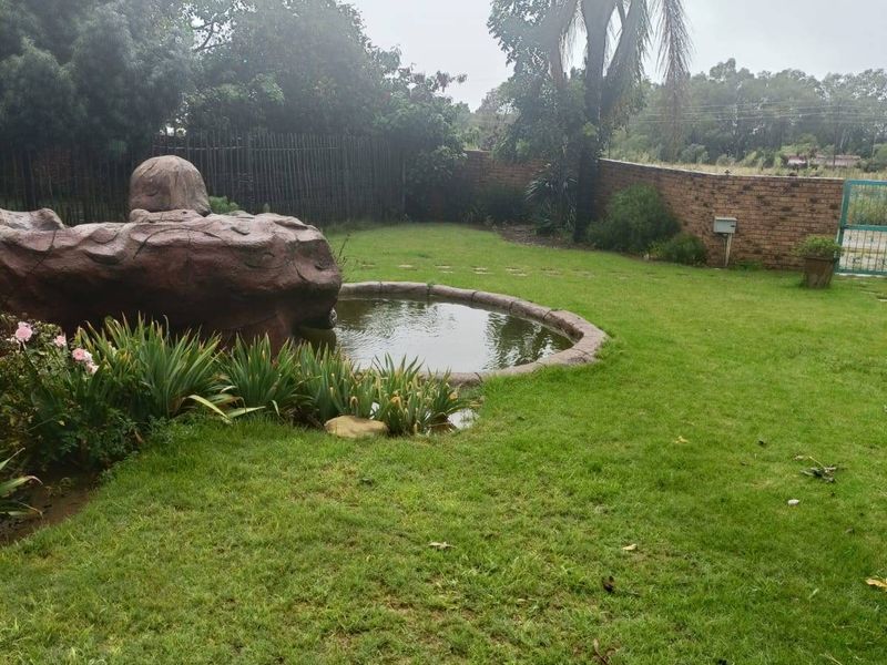 A private garden area featuring a landscaped pond with a decorative rock feature and enclosed by a brick boundary wall.
