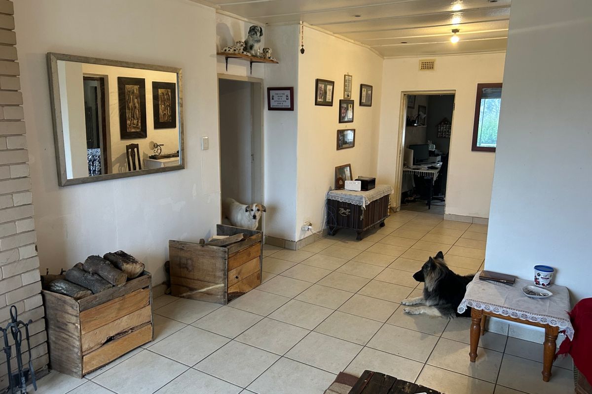Spacious living area featuring a brick fireplace, ceramic tiled flooring, and a timber ceiling, offering a functional layout with potential for cosmetic updates.