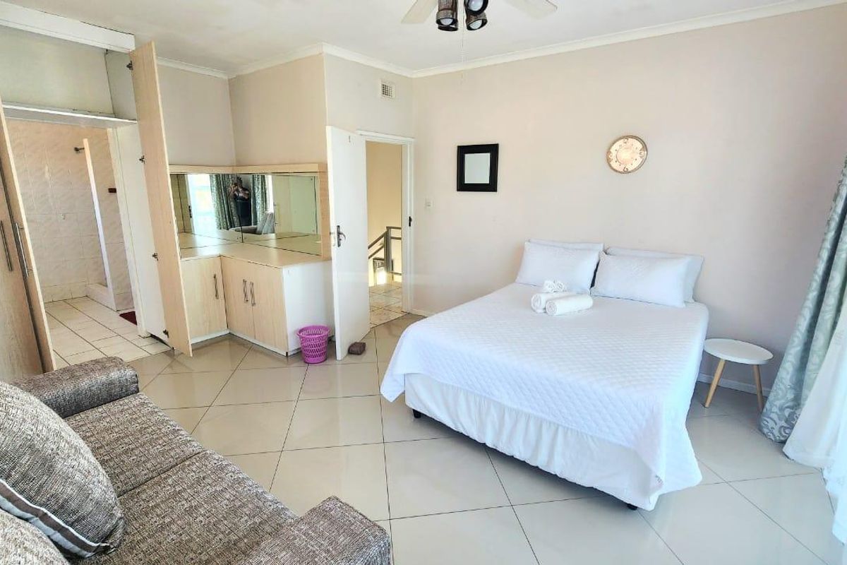 Spacious bedroom featuring tiled flooring, built-in cupboards, a ceiling fan, and direct access to an en-suite bathroom.