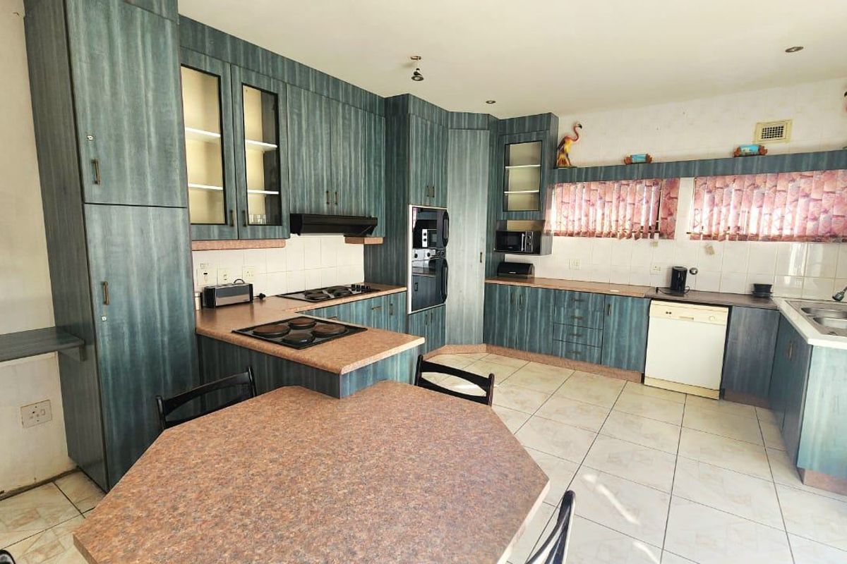 Spacious kitchen featuring extensive built-in cabinetry, laminate countertops, integrated oven, hob, and a double sink with tiled flooring and backsplash.