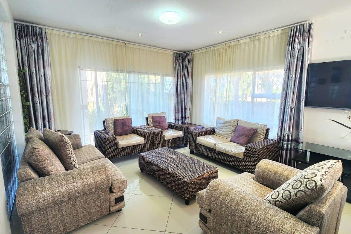 A bright and spacious living room featuring large sliding glass doors, tiled flooring, and a unique glass block feature wall.
