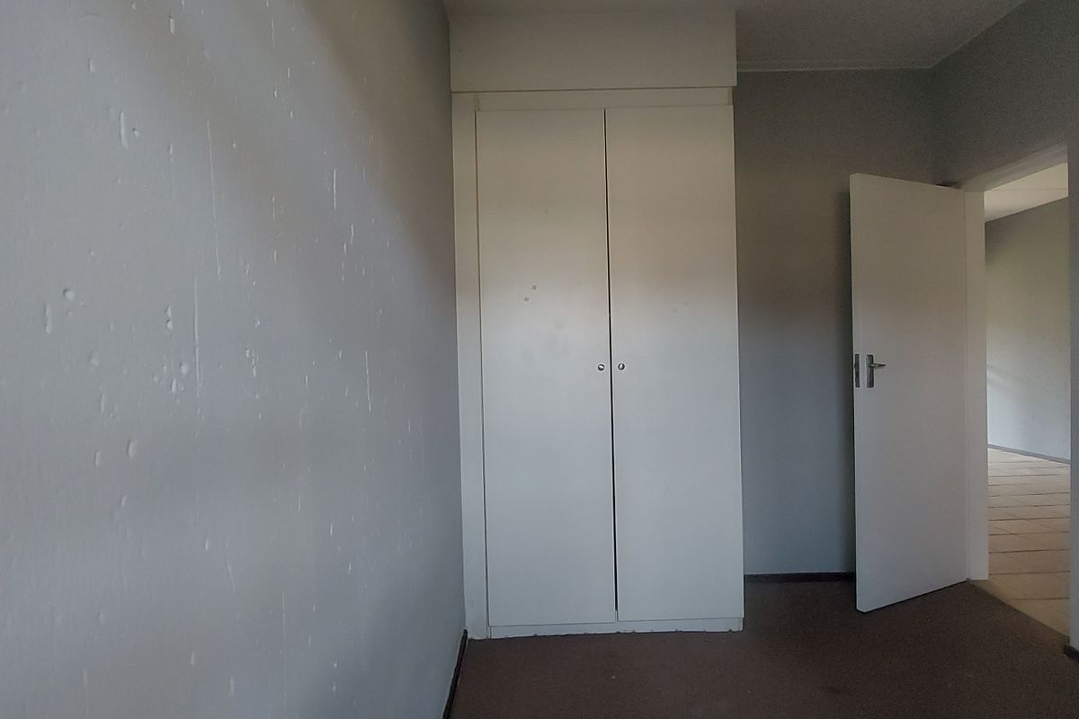 A vacant bedroom featuring built-in wardrobes, carpeted flooring, and neutral wall finishes, offering a blank canvas for personalization.