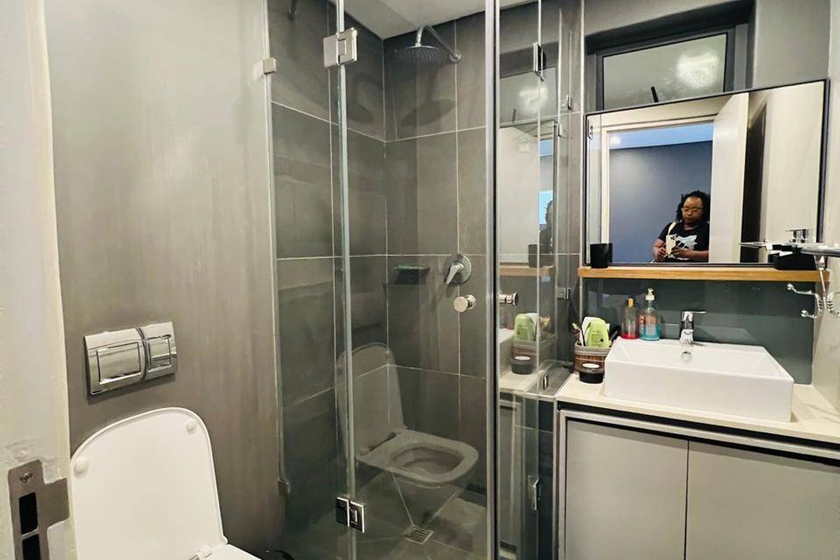 Modern bathroom featuring a glass-enclosed shower, wall-mounted toilet, and a sleek vanity with a vessel sink.