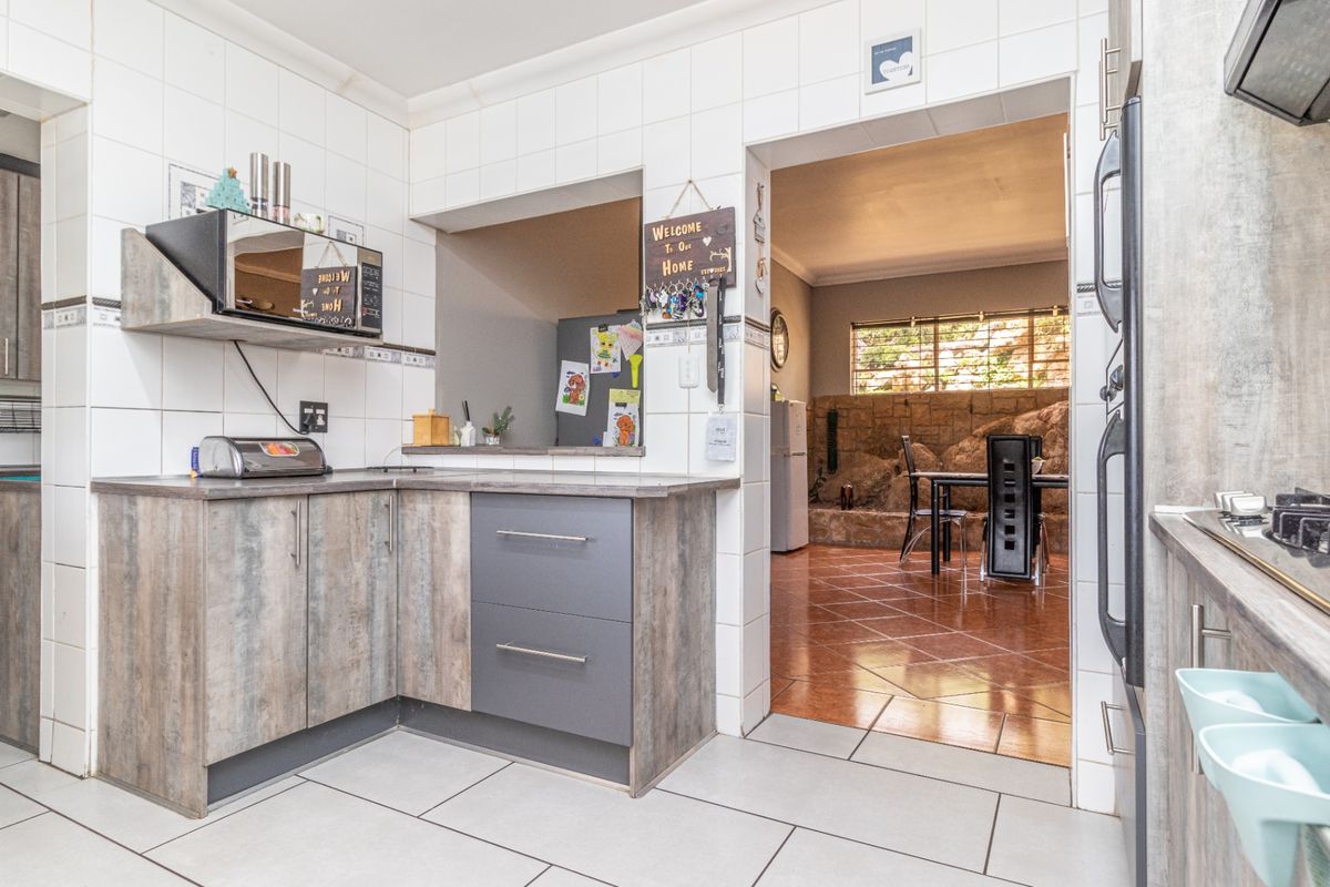 Functional kitchen featuring modern laminate cabinetry, built-in oven, hob, and a convenient pass-through window connecting to the adjacent dining area.