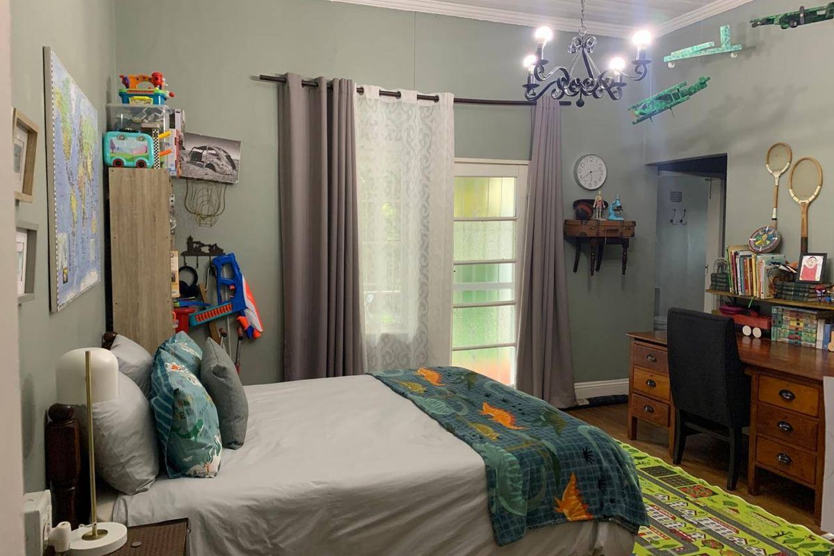 A bedroom featuring timber flooring, coved ceilings, a decorative chandelier, and a glass-paneled door providing access to the exterior.