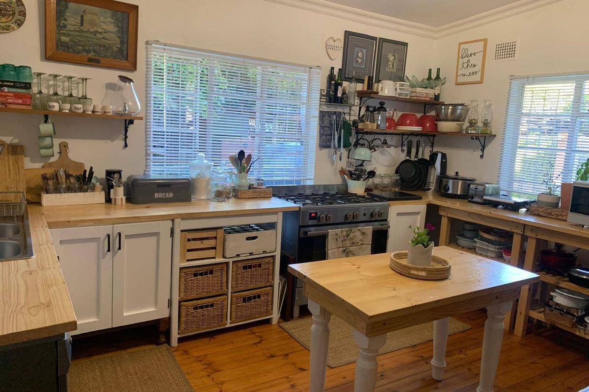 A rustic-style kitchen featuring timber flooring, wooden countertops, open shelving, and a gas stove, offering a warm and functional cooking space.