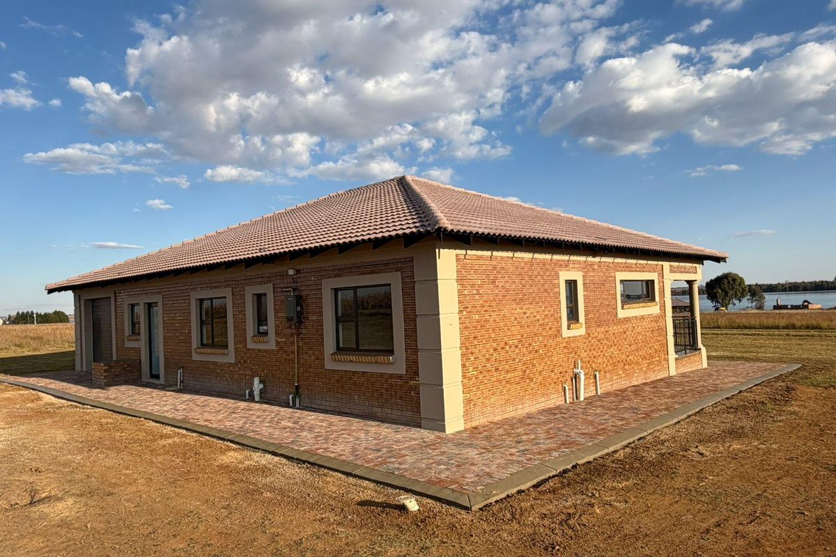Rear view of a modern face brick residential property featuring a tiled roof and paved perimeter walkway set on a spacious plot.