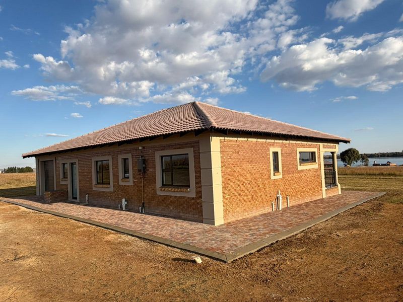 Rear view of a modern face brick residential property featuring a tiled roof and paved perimeter walkway set on a spacious plot.