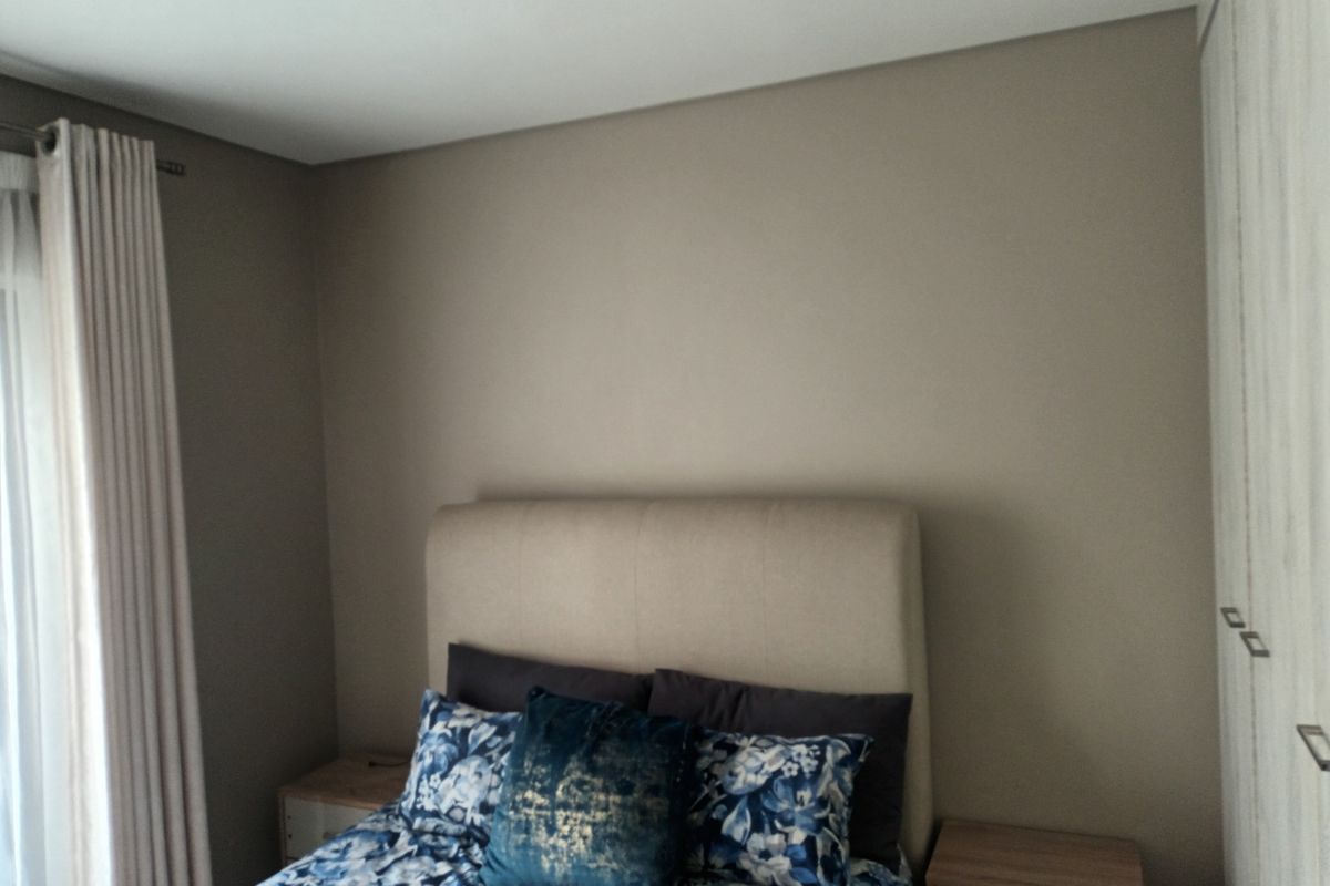 A well-maintained bedroom featuring neutral wall tones and integrated built-in cupboards, providing a clean and functional living space.