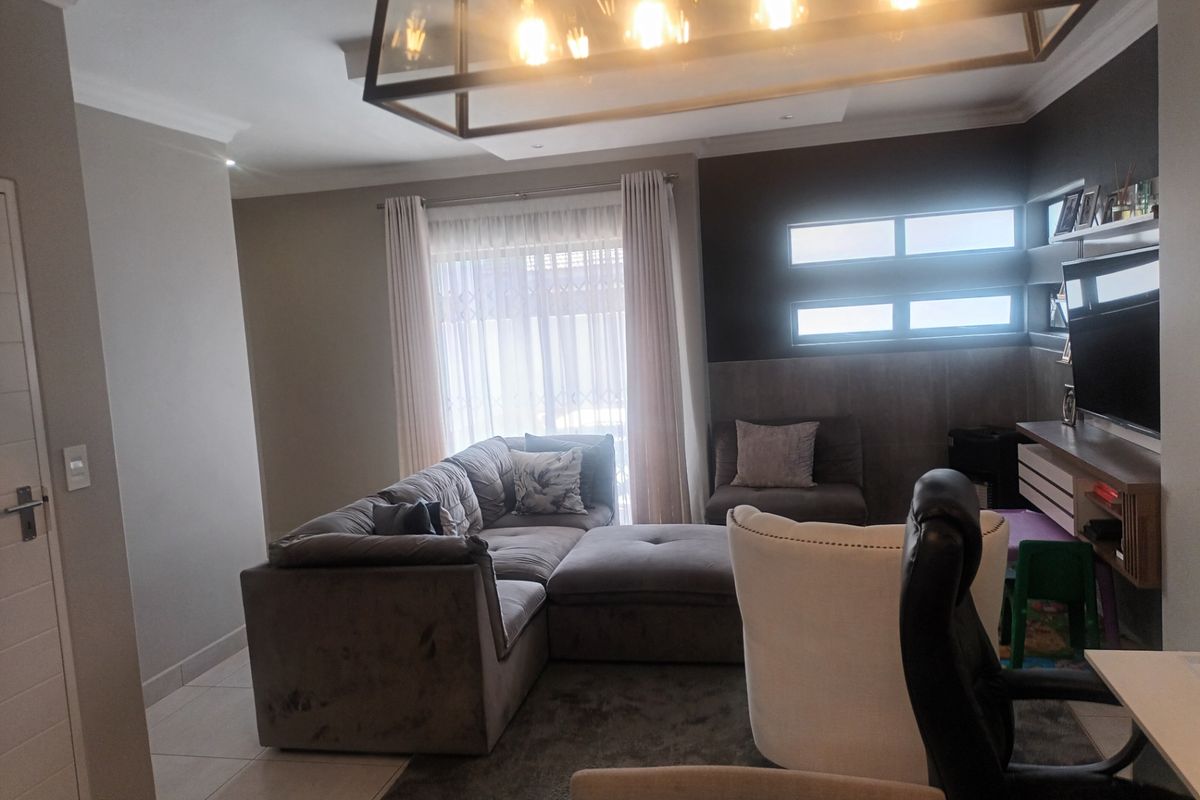 A well-lit living room featuring tiled floors, modern pendant lighting, and horizontal windows, creating a comfortable and contemporary living space.