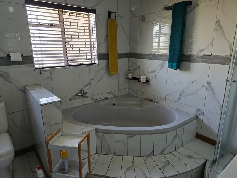 A modern bathroom featuring a corner bathtub, floor-to-ceiling marble-look wall tiles, and a separate shower enclosure.