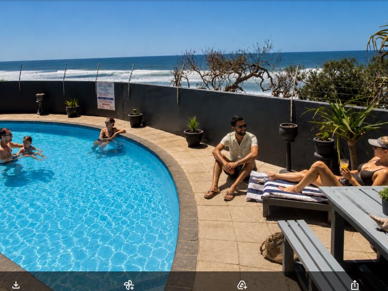 Outdoor swimming pool area featuring a paved deck, boundary wall with electric fencing, and direct ocean views.