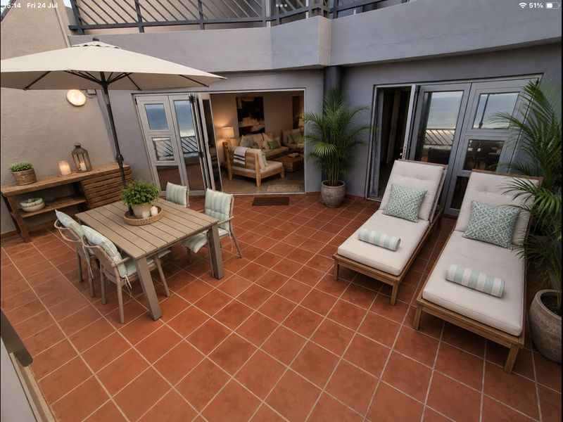 Spacious outdoor patio featuring terracotta tiling, aluminium sliding doors, and direct access to the living area, perfect for coastal entertaining.